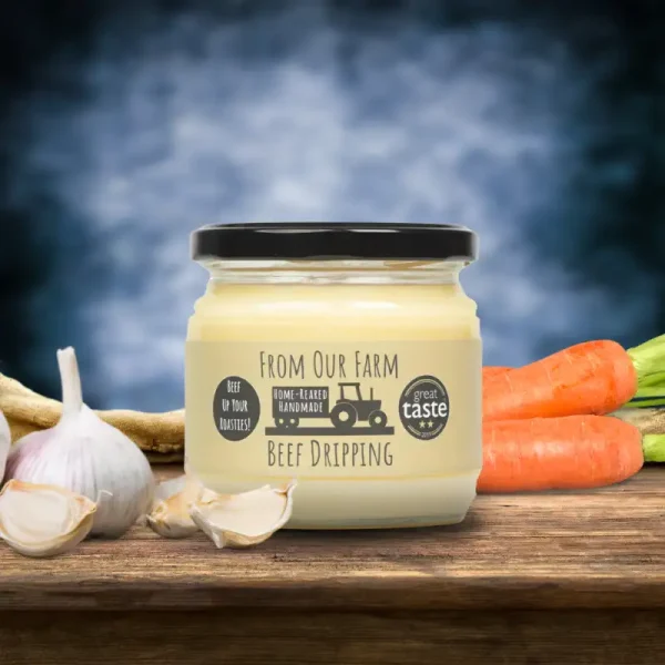 A jar of From Our Farm Beef Dripping displayed on a rustic wooden table, surrounded by fresh garlic, carrots, and vegetables, showcasing its premium quality and farm-fresh appeal.