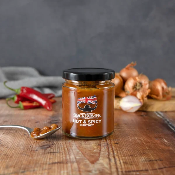 A jar of The Black Farmer’s Hot & Spicy Chutney, showcasing a bold red label and fiery spices within the chutney.