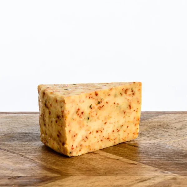 A triangular wedge of artisan Burner cheese infused with vibrant flecks of red chilli and herbs